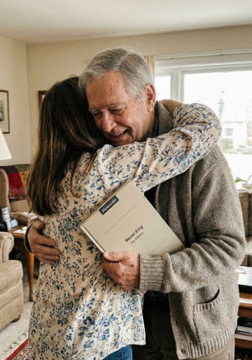 Father and daughter hugging after he receives his Memowrite book