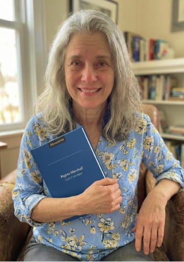 Woman holding her blue Memowrite life story book in an armchair